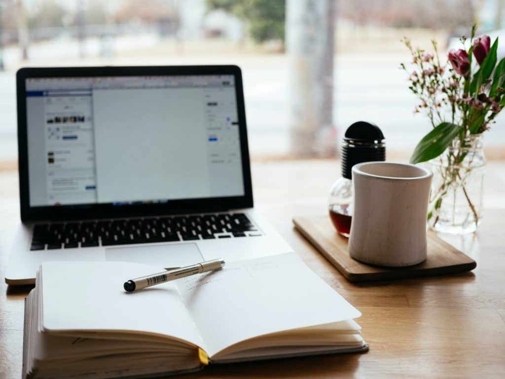 laptop, bilježnica i šalica kave prikaz su za online posao za studente koji su se odlučili za odlazak od kuće